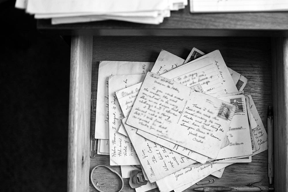 A desk drawer slid open to reveal a small stack of handwritten thank-you notes, one dated years ago