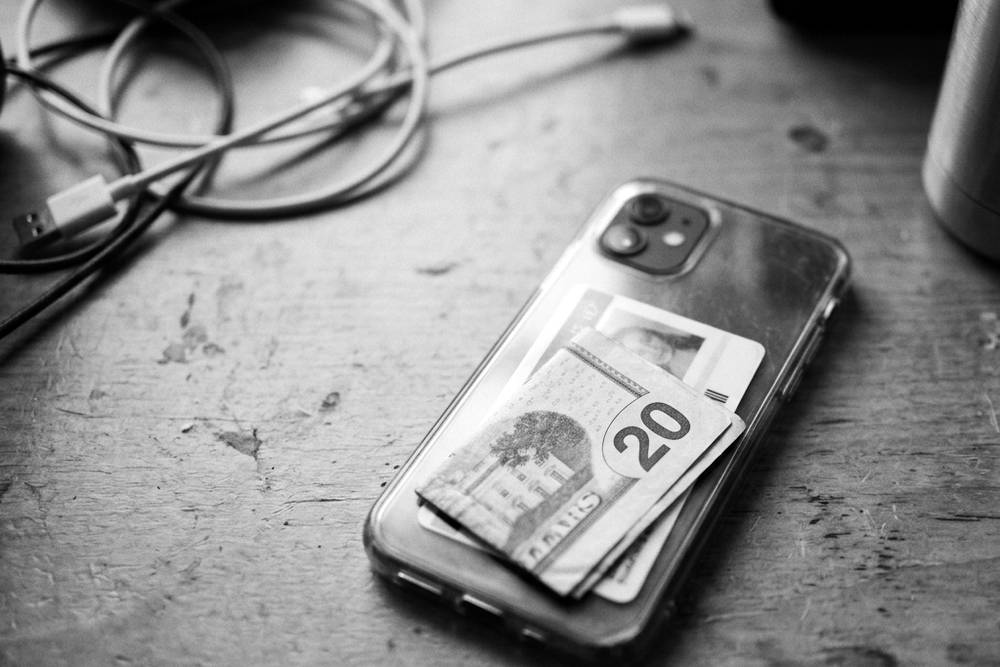 A single folded twenty tucked behind a student ID in a clear phone case