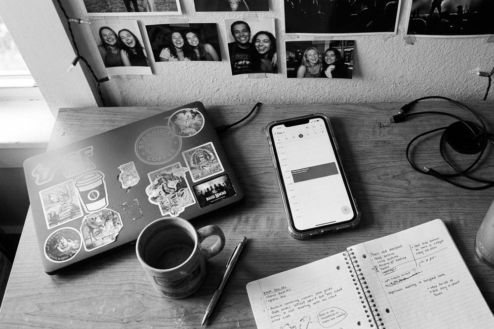 A phone face-up on a dorm desk showing a recurring Sunday calendar entry that reads 'call home.'